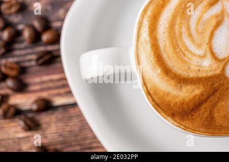 Köstliche Tasse heißen Cappuccino ist auf dem Holztisch. Es ist eine Kunst auf dem Latte Stockfoto