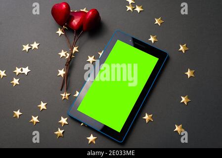 Kaufen Online-Geschenk für Ihren valentinstag, rote Herzen und grünen Bildschirm auf Tablet. Stockfoto