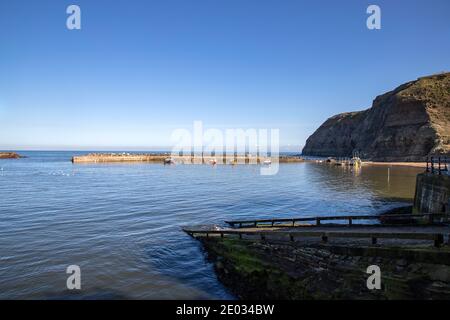 Staithes Hafen, ein einst wichtiger Fischerhafen, auch bekannt für seine einzigartigen und bunten "Cobles" Fischerboote, die noch Hummer und Makrelen fischen. Stockfoto