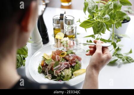 Salat mit Parmaschinken, Tomaten, gelber Rote Bete und Vinaigrette-Sauce. Appetitliches Gericht serviert auf einem weißen Teller. Kulinarische Fotografie. Stockfoto