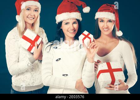 Drei Frauen im Kostüm des Weihnachtsmannes mit Weihnachtseinkäufen. Stockfoto