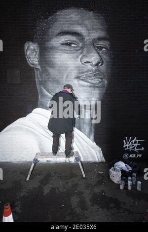 Street Artist Akse, steht vor seinem Wandbild des Fußballstars Marcus Rashford. Stockfoto