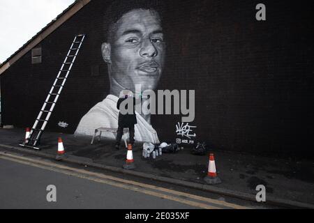 Street Artist Akse, steht vor seinem Wandbild des Fußballstars Marcus Rashford. Stockfoto