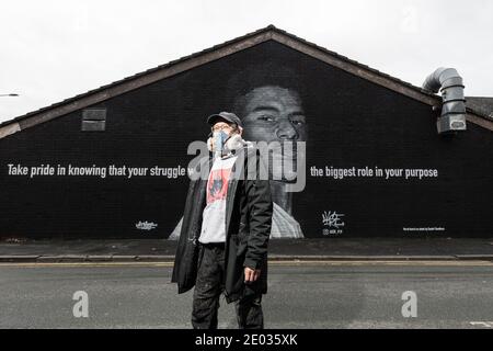 Street Artist Akse, steht vor seinem Wandbild des Fußballstars Marcus Rashford. Stockfoto