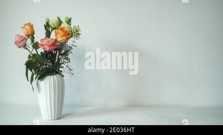 Strauß Rosen und Gypsophila in weißer Vase, weißer Hintergrund, Inneneinrichtung, Kopierraum Stockfoto