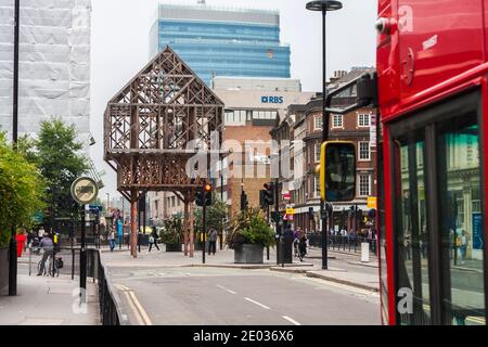 Eine Straßenszene in Aldgate in London, England, UK mit dem Holz Struktur genannt Paleys auf Pilern im Hintergrund Stockfoto