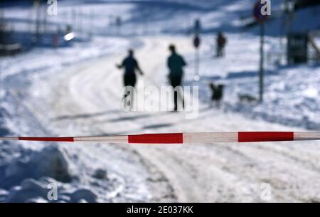 Nesselwang, Deutschland. Dezember 2020. Wanderer laufen hinter einer Schranke für Autos an der Talstation der geschlossenen Alpspitzbahn. Quelle: Karl-Josef Hildenbrand/dpa/Alamy Live News Stockfoto