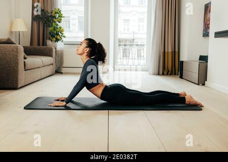 Seitenansicht der Frau, die Stretching-Übungen auf der Matte macht Zu Hause Stockfoto