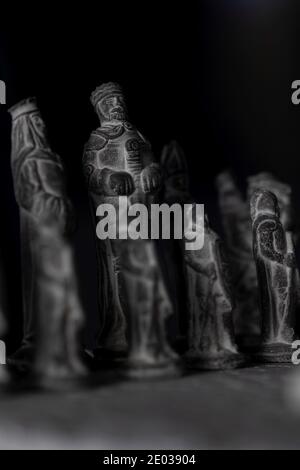 Ein Porträt der schwarzen Steinarmee auf einem Steinchessboard. Sie sind für den Beginn des strategischen Matches eingerichtet. Stockfoto