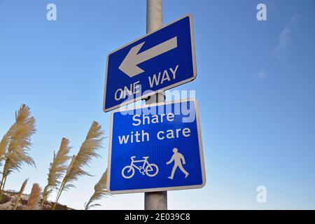 Blaue und weiße Schilder: One Way mit Pfeil, und teilen mit Aktien mit Fahrrad und Fußgänger Symbole. Stockfoto