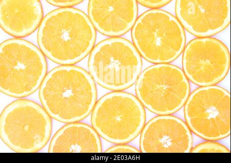 Helle Überkopfansicht frischer orangefarbener Scheiben, die im Muster vor weißem Hintergrund angeordnet sind Stockfoto