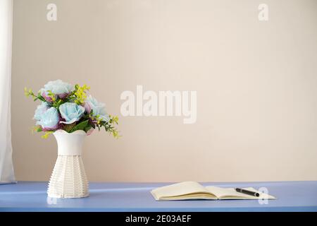 Blaue Blumen in Vase und offenes Notizbuch mit Stift auf Tisch. Speicherplatz kopieren Stockfoto