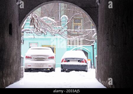 Autos auf einer mit Schnee bedeckten Straße geparkt. Nach Schneesturm, Kiew, Ukraine Stockfoto