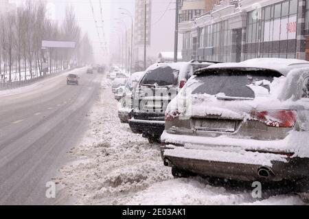 Autos auf einer mit Schnee bedeckten Straße geparkt. Nach Schneesturm, Kiew, Ukraine Stockfoto