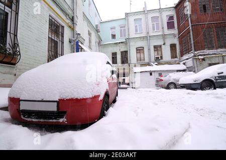 Autos auf einer mit Schnee bedeckten Straße geparkt. Nach Schneesturm, Kiew, Ukraine Stockfoto