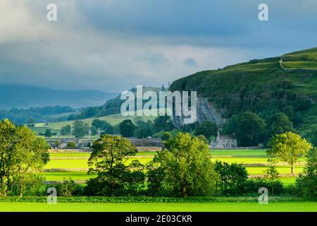 Malerisches Wharfe Valley (flache sonnendurchflutete Felder, Steinmauern, Kilnsey Crag - hohe Kalksteinfelsen, sanfte Hügel) - Wharfedale, Yorkshire Dales, England, Großbritannien.