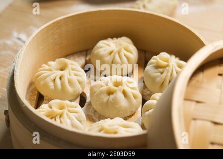 Nahaufnahme von rohen Brötchen in Bambus-Dampfgarer, handgemachte Baozi, hausgemachte chinesische Küche Stockfoto