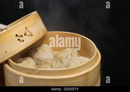 Gedünstete Schweinebraten, Nahaufnahme von Brötchen in Bambusdampfer, schwarzer Hintergrund, Baozi Stockfoto