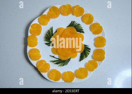 Goldorange Scheiben im Kreis um Teller angeordnet, Form der Blume in der Mitte, Draufsicht Stockfoto