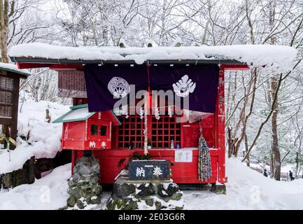 Dramatischer roter Torii-Tunnel Eingang zum Ana Mori Inari-Schrein im Sainokawara Park, Kusatsu Open Air Onsen, Japan. Stockfoto