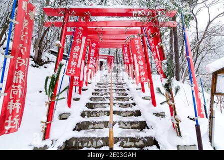 Dramatischer roter Torii-Tunnel Eingang zum Ana Mori Inari-Schrein im Sainokawara Park, Kusatsu Open Air Onsen, Japan. Stockfoto