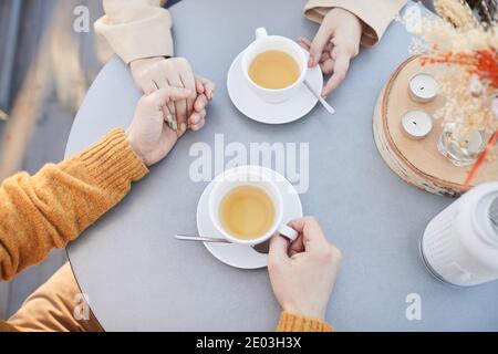 Nahaufnahme eines jungen Paares, das die Hände hält und dabei Tee trinkt Ihr romantisches Date im Restaurant Stockfoto