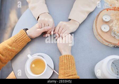 High-Winkel-Ansicht der liebevollen Paar hält sich gegenseitig für Hände beim Teetrinken am Tisch Stockfoto