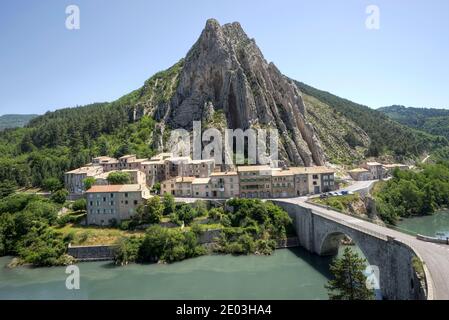 Kleines Dorf neben Durance River und Brücke zu Fuß Von kegelförmigen Berg in Sisteron Provence Frankreich in der Ausläufer der französischen Alpen Stockfoto