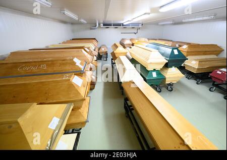 Dresden, Deutschland. Dezember 2020. In Kreide geschrieben ist 'Covid-19' auf einem Sarg mit einem Verstorbenen, der an oder mit dem Coronavirus gestorben ist, der sich im Krematorium Dresden-Tolkewitz in der Kälte mit anderen Särgen befindet. Das Krematorium hat aufgrund der hohen Übersterblichkeit bei der Corona-Pandemie die Kapazitätsgrenze erreicht und ist nun auf die Hilfe anderer Krematorien angewiesen. Quelle: Sebastian Kahnert/dpa-Zentralbild/dpa/Alamy Live News Stockfoto