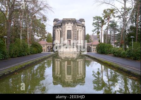 Dresden, Deutschland. Dezember 2020. Das Krematorium Dresden-Tolkewitz spiegelt sich in einem Wasserbecken wider. Das Krematorium hat aufgrund der hohen Übersterblichkeit bei der Corona-Pandemie die Kapazitätsgrenze erreicht und ist nun auf die Hilfe anderer Krematorien angewiesen. Quelle: Sebastian Kahnert/dpa-Zentralbild/dpa/Alamy Live News Stockfoto