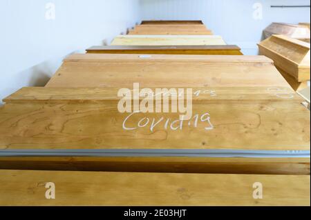 Dresden, Deutschland. Dezember 2020. In Kreide geschrieben ist 'Covid-19' auf einem Sarg mit einem Verstorbenen, der an oder mit dem Coronavirus gestorben ist, der sich im Krematorium Dresden-Tolkewitz in der Kälte mit anderen Särgen befindet. Das Krematorium hat aufgrund der hohen Übersterblichkeit bei der Corona-Pandemie die Kapazitätsgrenze erreicht und ist nun auf die Hilfe anderer Krematorien angewiesen. Quelle: Sebastian Kahnert/dpa-Zentralbild/dpa/Alamy Live News Stockfoto
