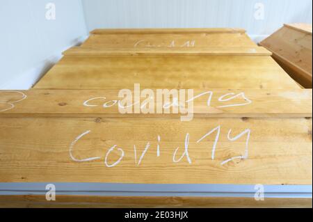 Dresden, Deutschland. Dezember 2020. In Kreide geschrieben ist 'Covid-19' auf einem Sarg mit einem Verstorbenen, der an oder mit dem Coronavirus gestorben ist, der sich im Krematorium Dresden-Tolkewitz in der Kälte mit anderen Särgen befindet. Das Krematorium hat aufgrund der hohen Übersterblichkeit bei der Corona-Pandemie die Kapazitätsgrenze erreicht und ist nun auf die Hilfe anderer Krematorien angewiesen. Quelle: Sebastian Kahnert/dpa-Zentralbild/dpa/Alamy Live News Stockfoto