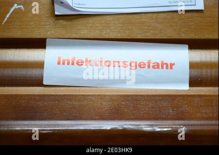 Dresden, Deutschland. Dezember 2020. Auf einem Sarg im Krematorium Dresden-Tolkewitz steckt ein Schild mit der Aufschrift "Ansteckungsgefahr". Das Krematorium hat aufgrund der hohen Übersterblichkeit bei der Corona-Pandemie die Kapazitätsgrenze erreicht und ist nun auf die Hilfe anderer Krematorien angewiesen. Quelle: Sebastian Kahnert/dpa-Zentralbild/dpa/Alamy Live News Stockfoto