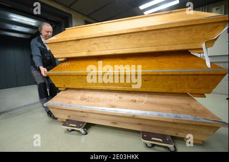 Dresden, Deutschland. Dezember 2020. Claus-Dieter Turra, Kremator, zieht Särge aus dem Kühlraum in einen Aufzug am Krematorium Dresden-Tolkewitz. Das Krematorium hat aufgrund der hohen Übersterblichkeit bei der Corona-Pandemie die Kapazitätsgrenze erreicht und ist nun auf die Hilfe anderer Krematorien angewiesen. Quelle: Sebastian Kahnert/dpa-Zentralbild/dpa/Alamy Live News Stockfoto