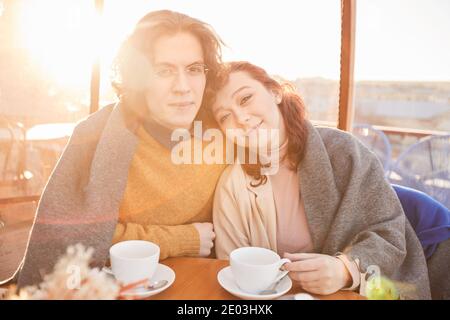Porträt von schönen Paar lächelt an der Kamera, während Tasse genießen Von Tee und einander im Café Stockfoto