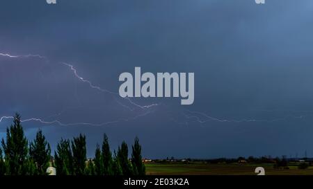 Ein starker Sturm über die Landschaft mit riesigen Blitz und Donner beim ersten Licht des neuen Tages Stockfoto