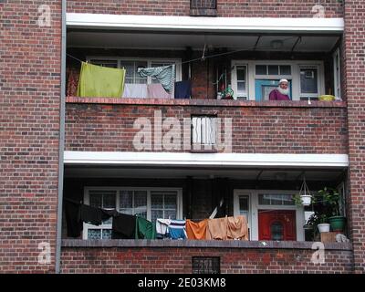 Mann auf dem Balkon von Shadwell rat sozialen Wohnimmobilien in Tower Hamlets Docklands London Großbritannien Stockfoto