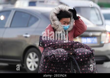 (201229) -- PEKING, 29. Dezember 2020 (Xinhua) -- EINE Frau Pedale ihr Fahrrad gegen den Wind auf einer Straße im Chaoyang Bezirk, Peking, Hauptstadt von China, 29. Dezember 2020. Chinas meteorologische Behörde hat am Dienstag eine orangene Warnung erneuert, die zweithöchste in einem vierstufigen Warnsystem, für eine kalte Welle, da eine starke Kaltfront seit Montag über die meisten Teile von Zentral- und Ostchina hinwegfegt. (Xinhua/Ju Huanzong) Stockfoto