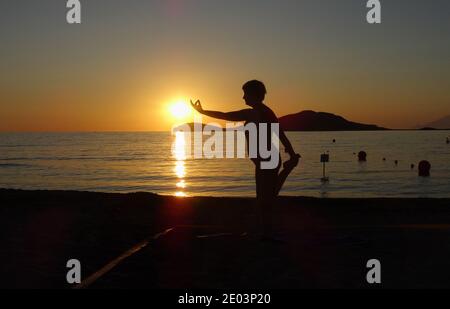 Lemnos Griechenland 15 September 2017 Yoga bei Sonnenuntergang am Plati Beach, Myrina, Lemnos Insel auf den griechischen Inseln mit Blick auf Loutra im Hintergrund Stockfoto