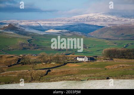 Lower Winskill Farm an einem sonnigen Wintertag mit den schneebedeckten Kalksteinnarben der Yorkshire Dales umrahmt die Szene dahinter. Stockfoto