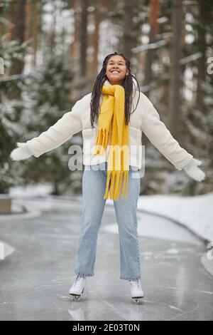 Glückliche afrikanische Frau in warmer Kleidung genießen ihre Zeit auf Skating-Ring im Winter Stockfoto