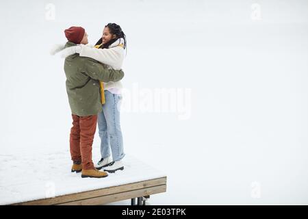 Junges glückliches Paar umarmt sich gegenseitig stehend auf dem Holz Brücke während ihrer Wanderung im Winter Stockfoto
