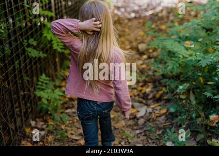 Kleines Mädchen kratzt Kopf beim Wandern im Wald Stockfoto