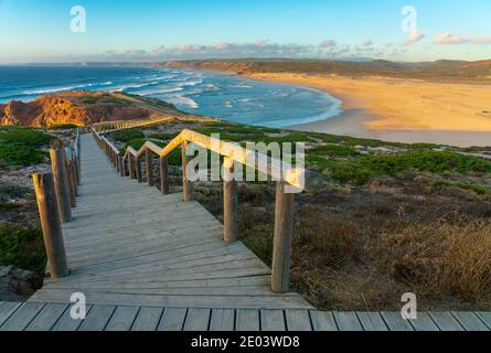 Praia da Bordeira in Algarve Portugal bei Sonnenuntergang mit Holz Gehweg im Vordergrund Stockfoto