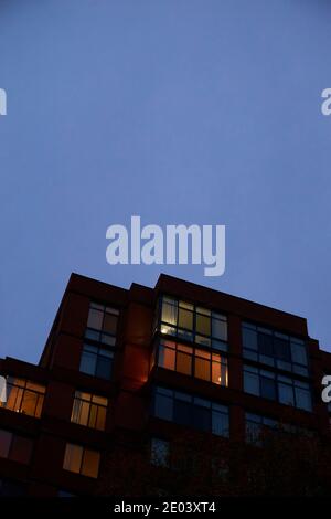 Ein launischer, beängstigender Blick auf ein sich in der Dämmerung aufbahnendes Apartmentgebäude mit einem bewölkten, grauen Himmel. In Arlington, Virginia. Stockfoto