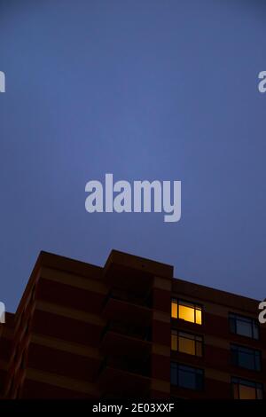 Ein launischer, beängstigender Blick auf ein sich in der Dämmerung aufbahnendes Apartmentgebäude mit einem bewölkten, grauen Himmel. In Arlington, Virginia. Stockfoto