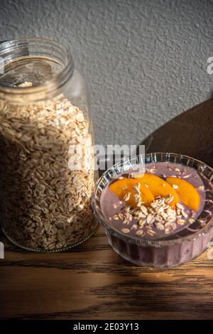 Acai Smoothie, Müsli, Samen, frisches Obst in einer Glasschale auf einem Holztisch. Essen gesunde Frühstückschale. Hochwertige Fotos Stockfoto