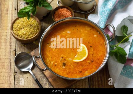 Türkische Küche. Traditionelle Suppe mit Reis, Linsen und Minze auf einem rustikalen Tisch. Stockfoto