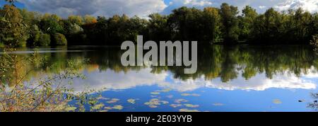 Herbst Farben über den See in Barnwell Country Park, Oundle, Northamptonshire, England, Großbritannien Stockfoto