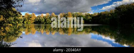 Herbst Farben über den See in Barnwell Country Park, Oundle, Northamptonshire, England, Großbritannien Stockfoto